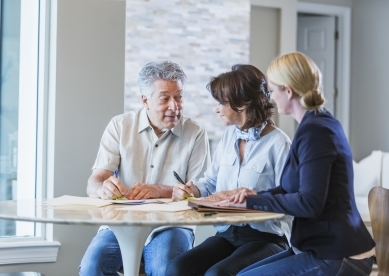 Three adults meeting and signing documents